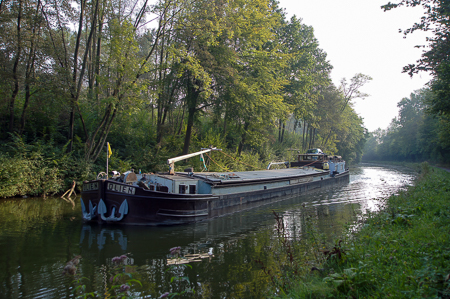 Mit dem Rad von Blaton zur Archéosite de Aubechies. Mit 38 m Länge eher ein Wicht unter den heutigen Binnenschiffen dümpelt auf dem Kanal Ath-Blaton
