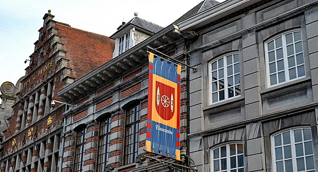 Belgien - Tournai in Wallonien - Historischer Hintergrund: Mit Zunftfahnen wird an den Fassaden der Grand‘ Place an alte Berufe erinnert, auch an die Teppichweber