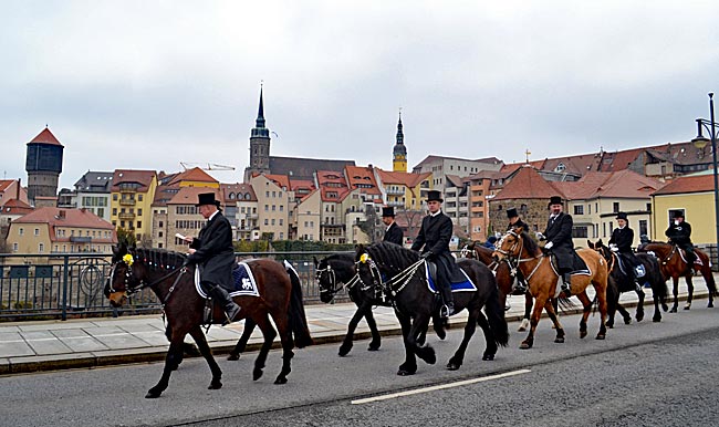 Bautzen - Auf dem Weg, die Osterbotschaft zu verkünden: Die Bautzener Osterreiter überqueren die Friedensbrücke vor dem Altstadtpanorama