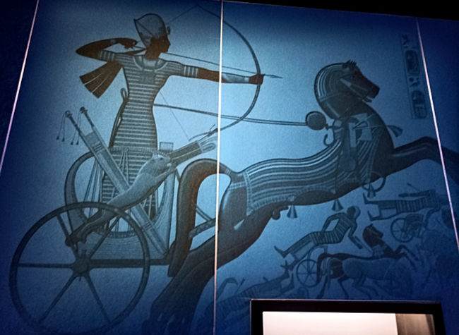 Odysseum, Ausstellung, Multimedia: Als Schlüsselfaktor zur militärischen Überlegenheit Ägyptens in der 18. Dynastie wurden die Streitwagen zum Symbol für die Führungsrolle des Pharaos. Auf einem Streitwagen, die Zügel um die Hüfte gebunden und mit einem Bogen bewaffnet, führt Ramses seine Truppen in die Schlacht.