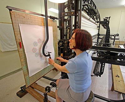 Vogtland - Ingrid Eichert zeigt Besuchern in der Schaustickerei im Ortsteil Reusa die Technik der Stickereimaschinen