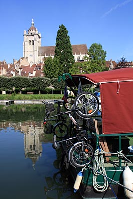 Frankreich - Yachthafen in Dole mit der Stiftskirche Notre Dame im Hintergrund und Hausboot mit Fahrrädern im Vordergrund