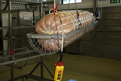 Bologna - Mortadella - Das Kunstwerk wird schließlich vorsichtig auf Gestellen mit Geflecht aus Stahl abgelegt