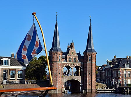 Niederlande -  Leeuwarden - Früher Teil der Stadtbefestigung, heute Wahrzeichen: Das Wassertor in Sneek von 1613, das einzige seiner Art in den Niederlanden. Die friesische Fahne (mit Herzchen), flattert von einem Schiffsbug ins Bild.