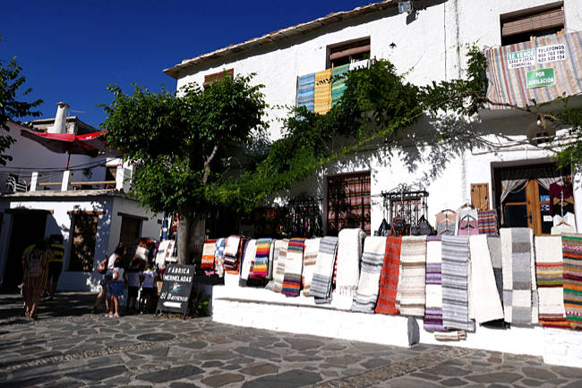 Verkauf von Flickenteppichen (jarapas) im Bergdorf Pampaneira in den Alpujarras, Sierra Nevada, Andalusien. Es gehört wegen seiner arabisch anmutenden Architektur zusammen mit Capileira und Bubión zu den schönsten Dörfern Spaniens
